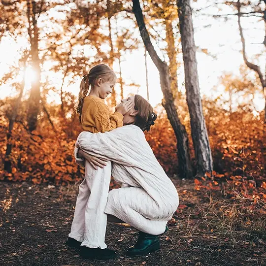 kobieta przytulająca dziecko w lesie