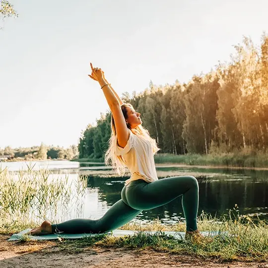 kobieta ćwicząca jogę nad brzegiem jeziora